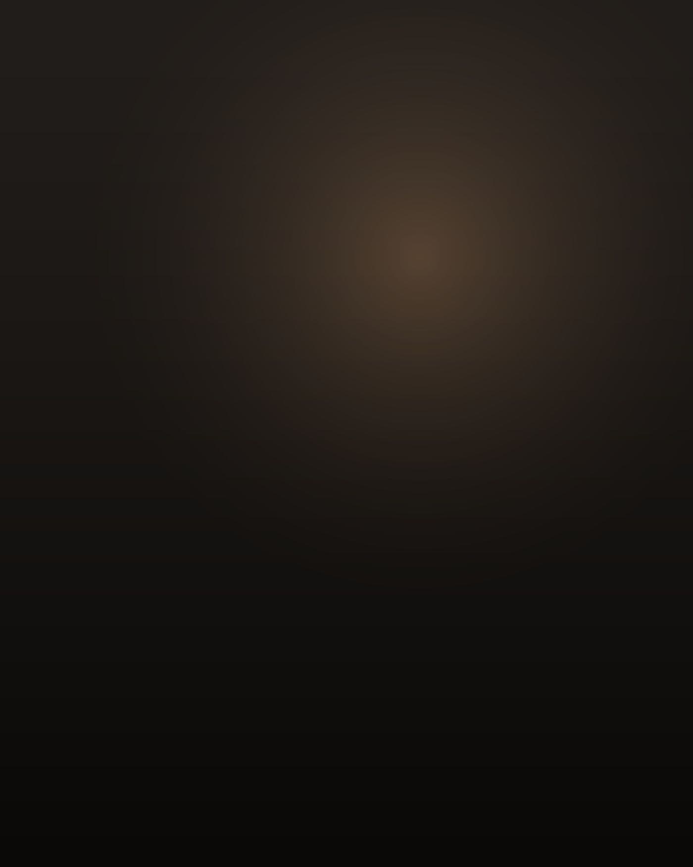 A nineteen-year-old East African man, Somali, very dark skin, extremely tall and rail thin with long arms and narrow shoulders, close-cropped hair, in a thin hooded sweatshirt, photographed from behind and slightly above in the passenger seat of a parked sedan at night, knees folded up high, one shoulder against a fogged window, warm sodium streetlight leaking through the glass, most of the car interior in deep shadow, his face turned away toward the window and not visible.