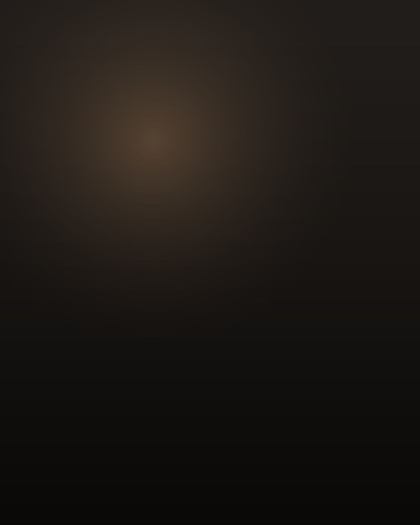 A short, heavy-built Black man in his late twenties, close-shaved head, thick neck and wide shoulders under a gray work t-shirt, standing in profile at a plastics press on a dark factory floor at night, lit low and warm from the machine itself, face turned away into deep shadow.